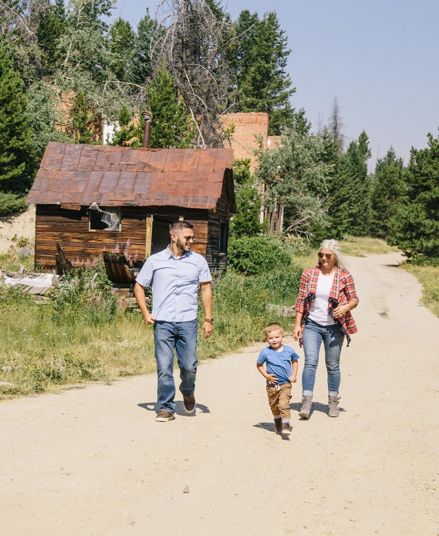A family of three walking down a dirt trail in Granite Ghost Town
