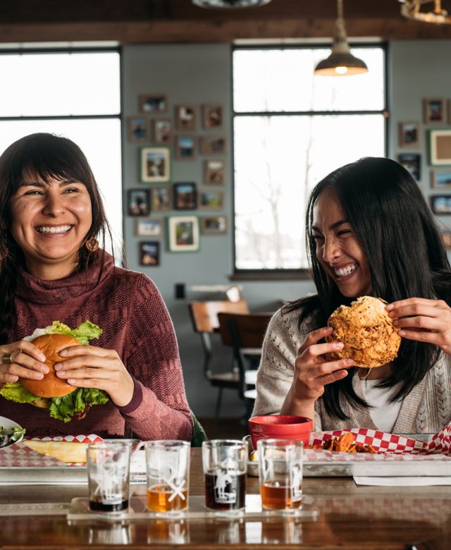 Two women eat cheeseburgers at Diamond X Beer Co in Billings along the Southeast Montana Burger Trail.