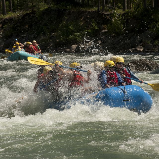 A group of people in a rubber raft riding the whitewater of Gallatin River