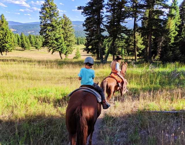 kids riding horses through Lone Mountain Ranch