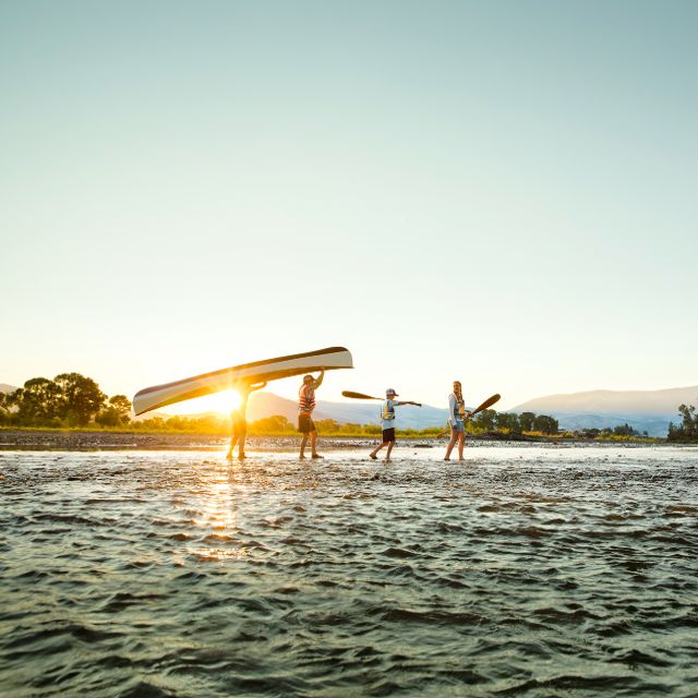 family carrying canoe across river