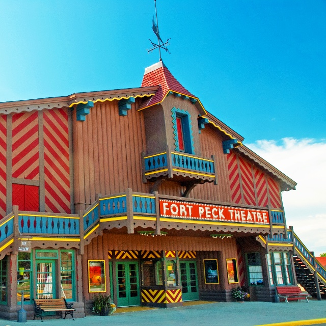 Colorful exterior front of the Fort Peck Theater, against a bright blue sky.