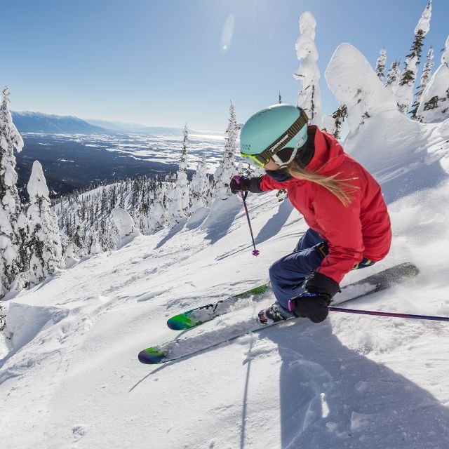 Skier in pink jacket skiing through trees