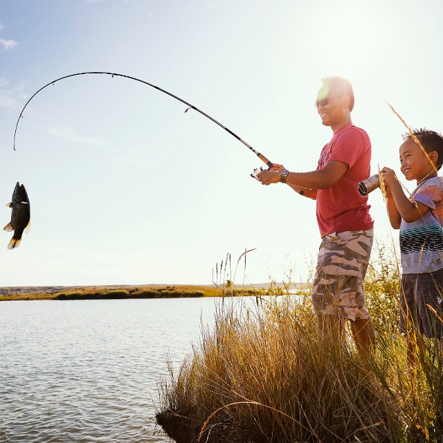 A son watching his father catch a fish.