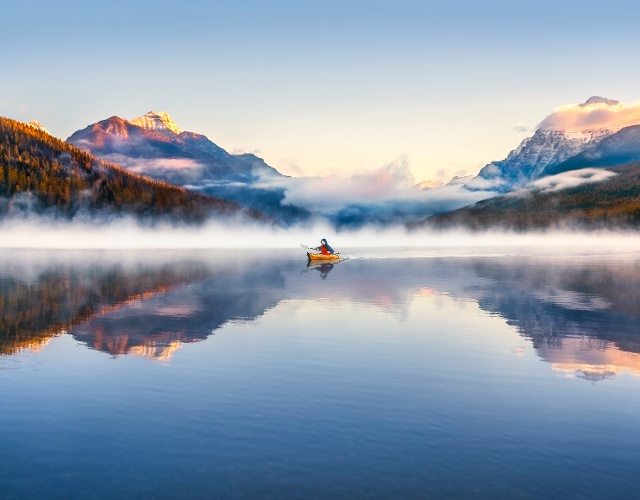 Kayaker on a fog-shrouded mountain lake