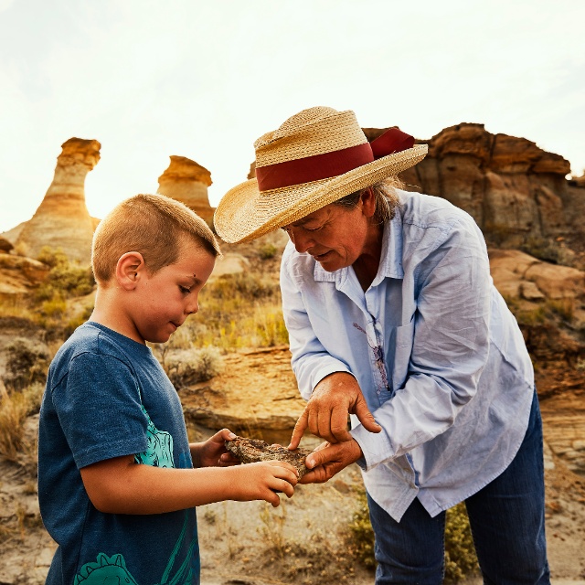 tour guide helping kid dig for dinosaur bones