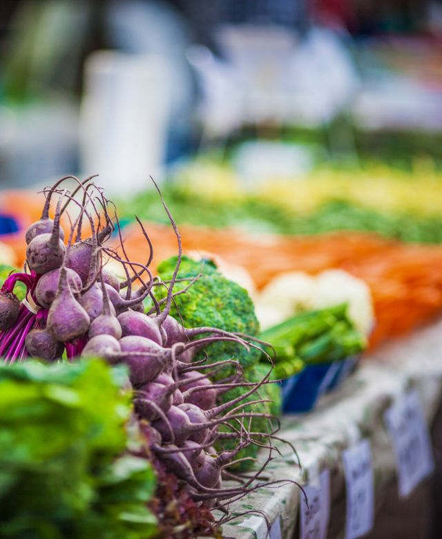 A colorful row of vegetables, including radishes, broccoli and carrots at farmer's market